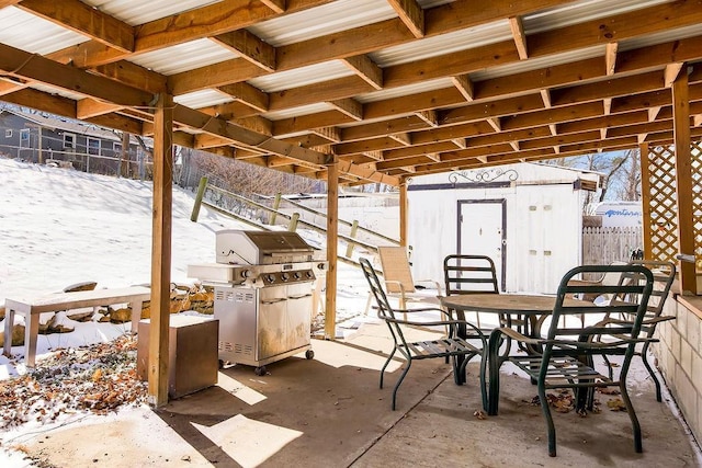 snow covered patio featuring an outbuilding, a shed, and fence