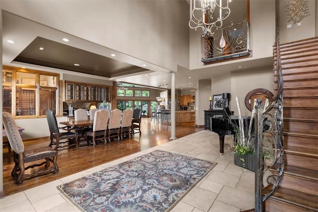 entryway with stairs, a tray ceiling, ornate columns, a notable chandelier, and recessed lighting