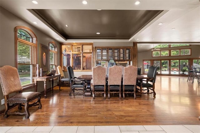 dining area featuring a wealth of natural light, a raised ceiling, and light wood finished floors