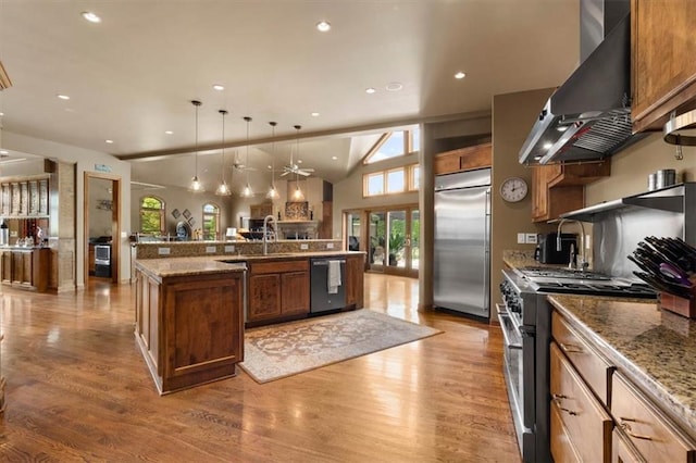 kitchen featuring hanging light fixtures, wall chimney exhaust hood, high quality appliances, and wood finished floors