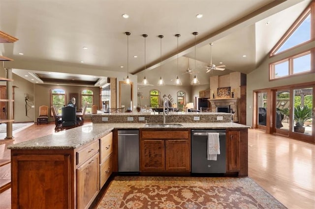 kitchen featuring light stone counters, a sink, open floor plan, hanging light fixtures, and dishwasher