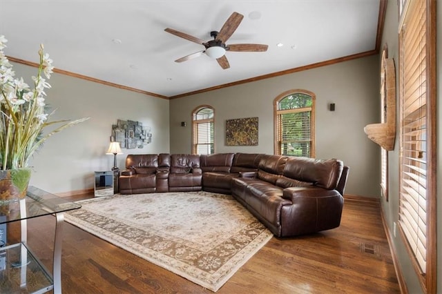 living area featuring baseboards, visible vents, a ceiling fan, wood finished floors, and crown molding