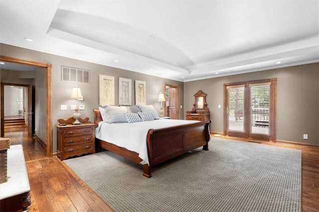 bedroom featuring wood finished floors, a raised ceiling, visible vents, and access to exterior