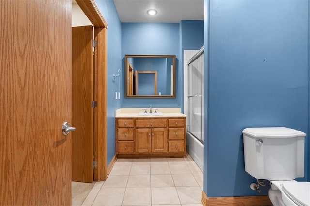 bathroom featuring toilet, shower / bath combination with glass door, vanity, baseboards, and tile patterned floors