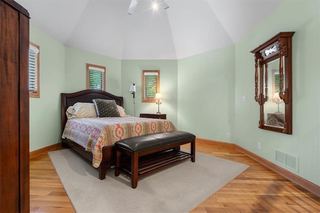 bedroom with light wood-type flooring, visible vents, vaulted ceiling, and baseboards