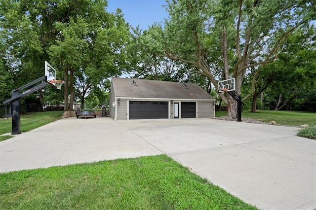 view of side of property featuring basketball hoop, a lawn, and a detached garage