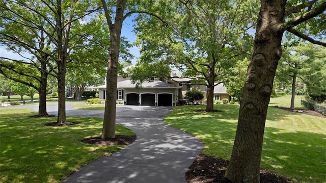 view of front facade featuring an attached garage, aphalt driveway, and a front yard