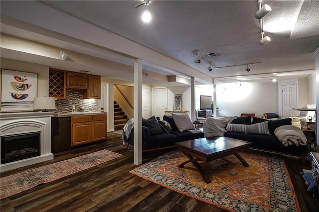 living area featuring visible vents, dark wood-style floors, stairway, a textured ceiling, and a fireplace