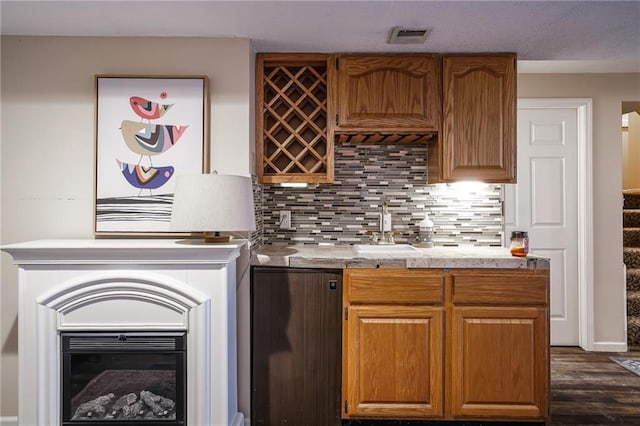 kitchen featuring a sink, visible vents, light countertops, decorative backsplash, and brown cabinets