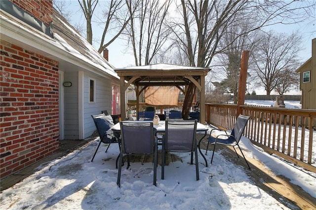 snow covered patio with outdoor dining area and a gazebo