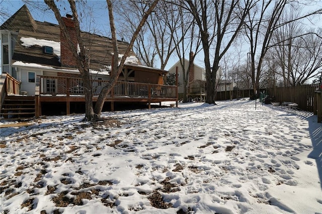 snowy yard featuring a deck and fence