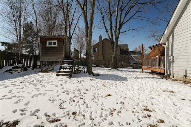 snowy yard featuring an outbuilding, a fenced backyard, and a storage unit