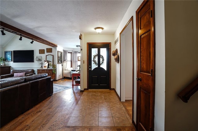 entryway featuring a textured ceiling, baseboards, wood finished floors, and track lighting