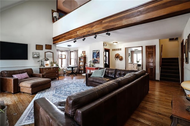 living area with dark wood-style floors, visible vents, beamed ceiling, and stairs