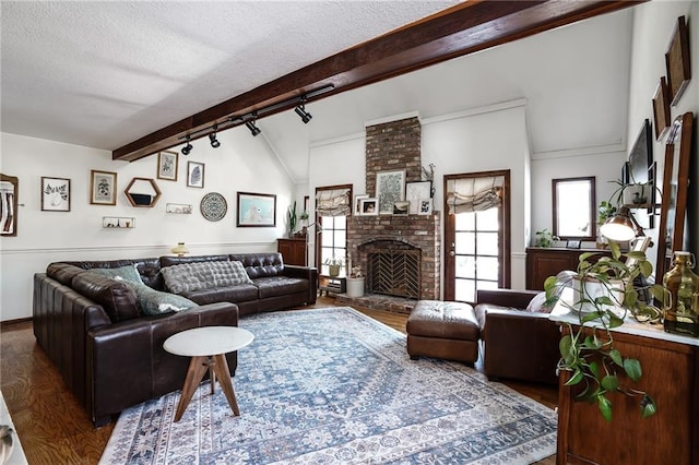 living area with dark wood-style floors, a fireplace, a textured ceiling, and track lighting