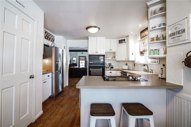 kitchen with black appliances, a peninsula, open shelves, and white cabinets