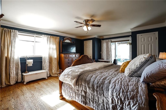 bedroom featuring light wood-type flooring, ornamental molding, and a ceiling fan