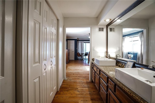 full bathroom with plenty of natural light, visible vents, a sink, and wood finished floors