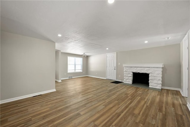 unfurnished living room featuring a fireplace, baseboards, dark wood-style flooring, and recessed lighting