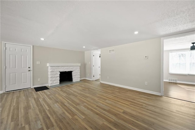 unfurnished living room with baseboards, a fireplace, visible vents, and wood finished floors