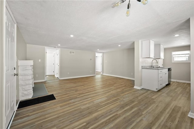 unfurnished living room featuring wood finished floors, a sink, and baseboards