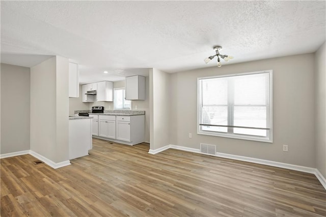 kitchen featuring light wood finished floors, visible vents, white cabinets, stainless steel electric range, and light countertops