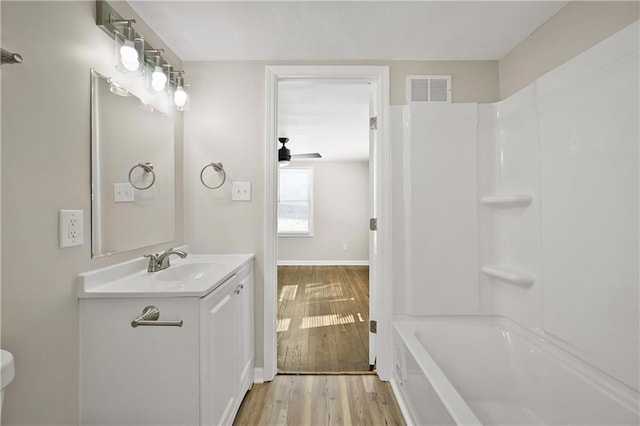 bathroom with baseboards, visible vents, wood finished floors, vanity, and shower / washtub combination