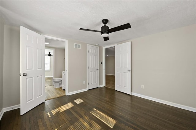 unfurnished bedroom featuring visible vents, a textured ceiling, baseboards, and dark wood-style flooring