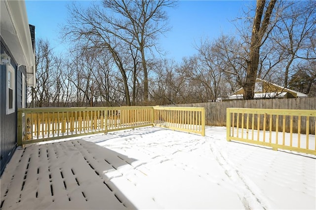 snow covered deck with a fenced backyard