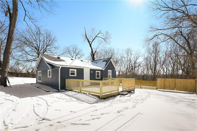 snow covered back of property with a deck and fence