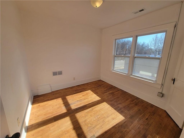 empty room with baseboards, visible vents, and wood finished floors
