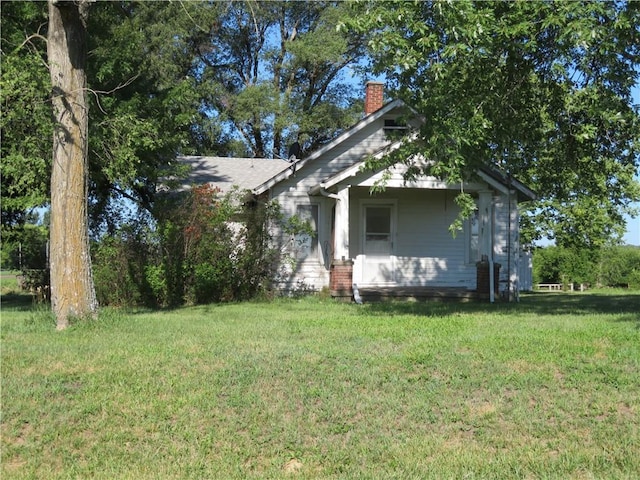 view of side of property featuring a chimney and a lawn