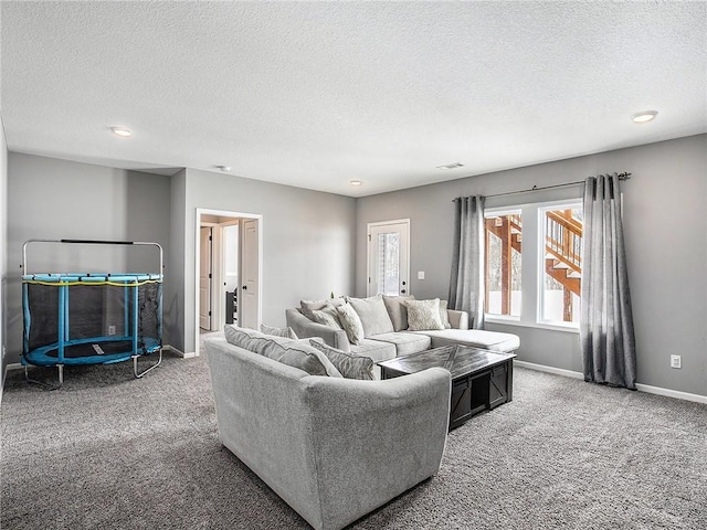 carpeted living area featuring baseboards and a textured ceiling