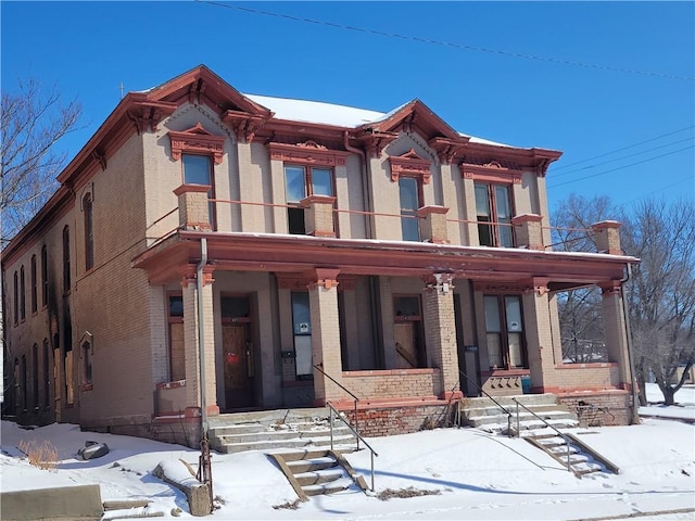 view of front of house featuring brick siding, a porch, and a balcony