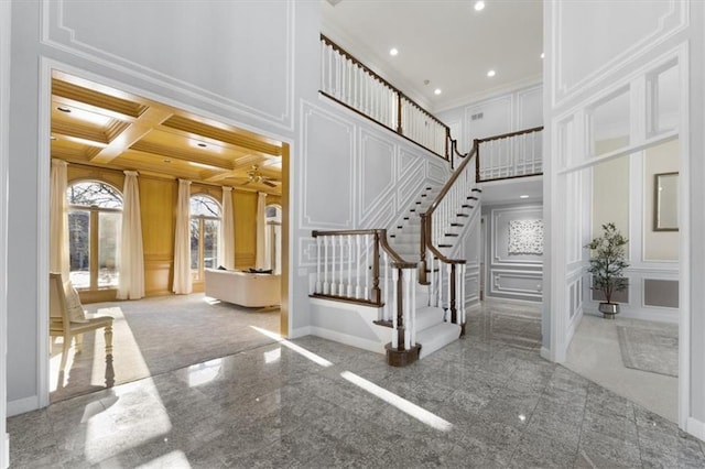 entrance foyer with granite finish floor, ornamental molding, and a decorative wall