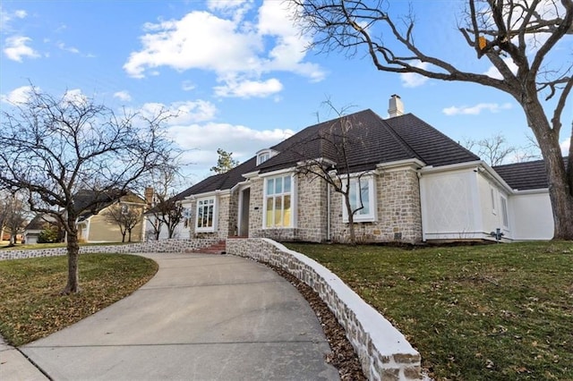 view of front facade featuring stone siding, a chimney, and a front lawn