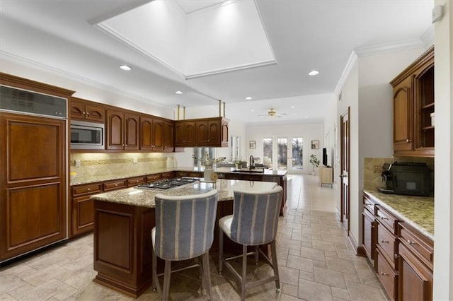 kitchen featuring built in appliances, a peninsula, a sink, a kitchen breakfast bar, and tasteful backsplash