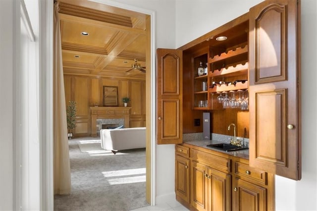 bar with indoor wet bar, light colored carpet, a premium fireplace, a sink, and coffered ceiling