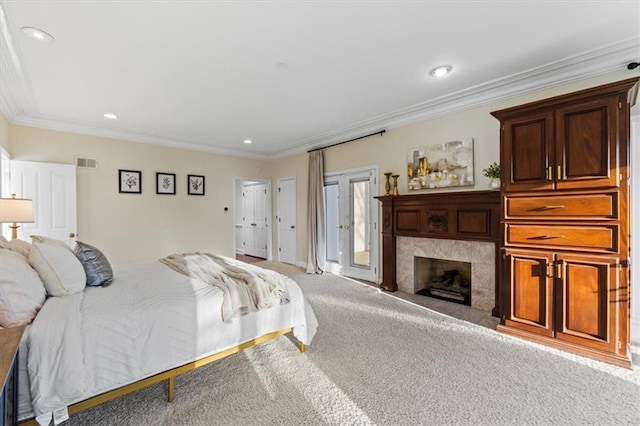 bedroom with light carpet, ornamental molding, a tiled fireplace, and visible vents