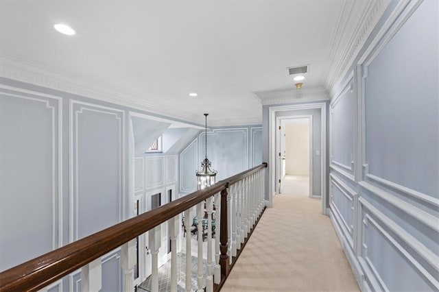 hallway with ornamental molding, recessed lighting, light colored carpet, and a decorative wall