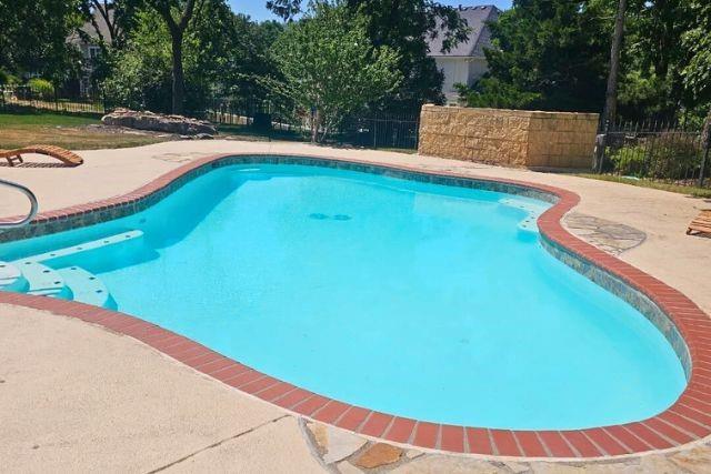 outdoor pool featuring a patio area and fence