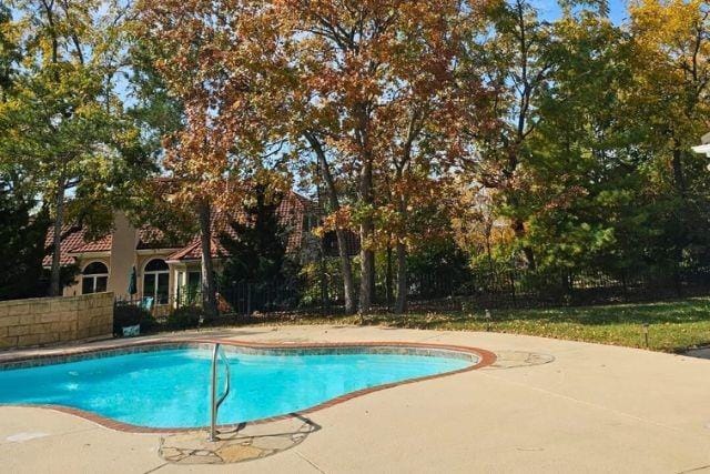 outdoor pool featuring a patio area and fence