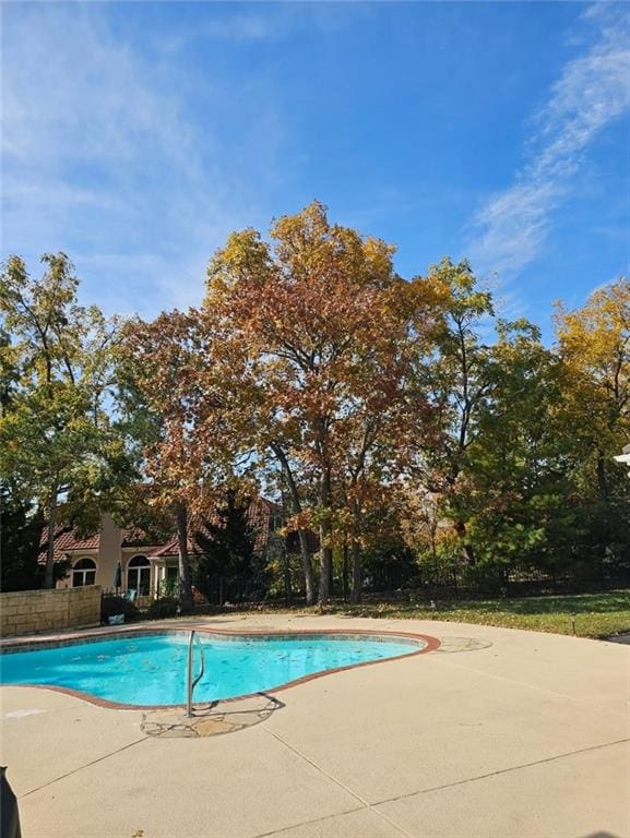 pool with a patio area and fence