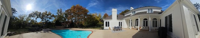 rear view of property featuring a patio and an outdoor pool