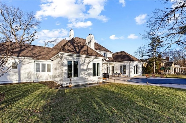 back of property with a yard, a chimney, and a patio area