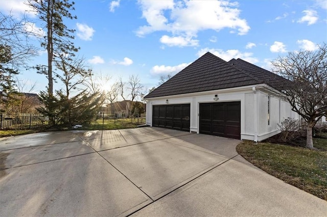 view of property exterior featuring a tiled roof, fence, and stucco siding