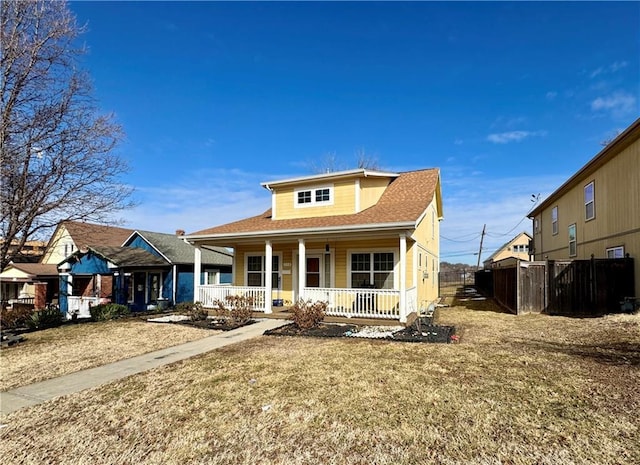 bungalow featuring a shingled roof, fence, a porch, and a front yard