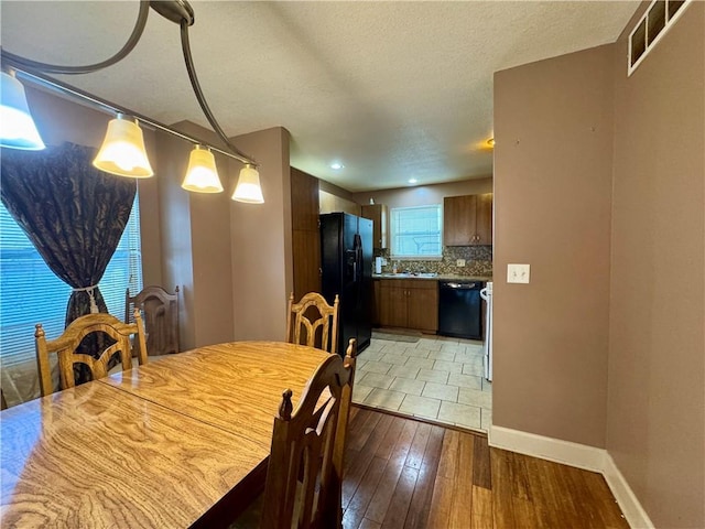 718 Oakland Ave, Kansas City, KS 66101 - dining room featuring baseboards, visible vents, a textured ceiling, and light wood finished floors