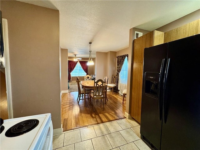718 Oakland Ave, Kansas City, KS 66101 - kitchen with light tile patterned floors, a textured ceiling, black fridge with ice dispenser, visible vents, and white range with electric stovetop