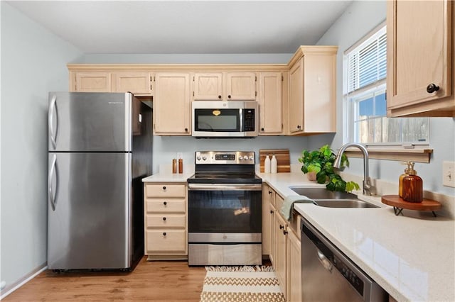 kitchen featuring stainless steel appliances, light countertops, a sink, and light wood finished floors